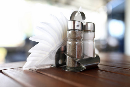 盐和胡椒瓶和餐巾纸的特写镜头站在桌子上香料的玻璃容器站在木桌上咖啡图片