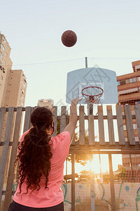 年轻的少女在城市篮球场上投掷篮球图片
