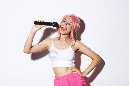 戴着粉色假发妆容艳丽用麦克风唱卡拉OK站在白色背景上的快乐美图片