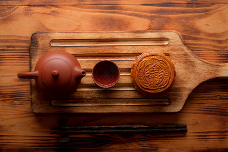 木板上传统月饼和茶具的顶视图月饼上的汉字用英文代表背景图片