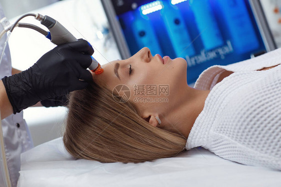 女在美容疗养院前额接受微红外膜治疗的侧面观察在美容科诊所进图片