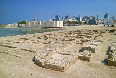 QalatalBahrain或巴林堡垒结构的遗迹及其博物馆和背景中的麦纳现代城市景观图片