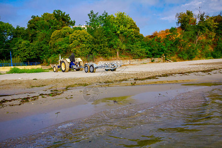 空拖车的拖拉机停在沙滩上等待运输船图片