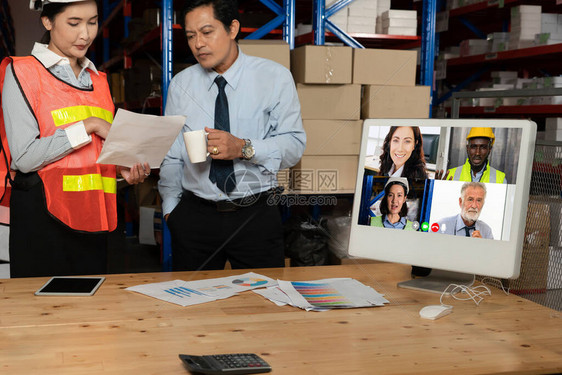 仓库工作人员在存储仓库的电脑屏幕上进行视频通话在线软件技术通过互联网络上的虚拟电话会议将在物流工厂作的图片
