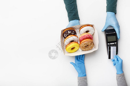 在covid大流行期间快餐和订购付款戴橡胶手套的服务员给了一盒甜圈图片