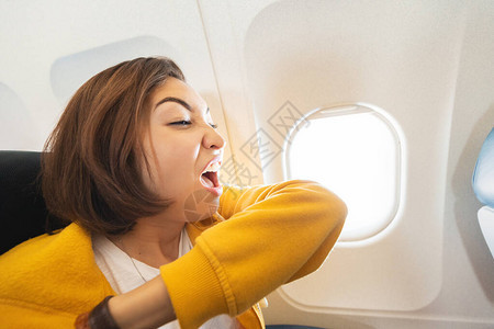 女飞机乘客打喷嚏到她的肘部航空运输过程中出现冠状和covid19感图片