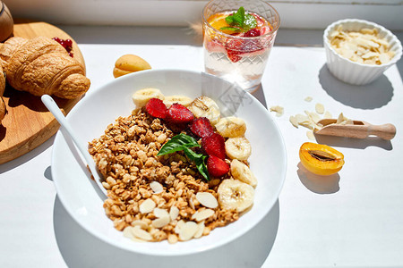 健康的早餐碗新鲜的格兰诺拉麦片麦片草莓白桌上的香蕉硬灯顶视图复制空间清洁饮食排毒节背景图片