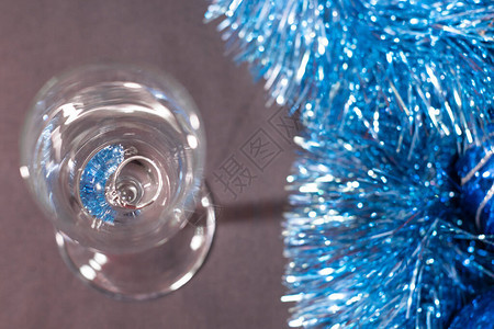 在一个香槟杯中订婚戒指在蓝色闪亮的圣诞树罐子附近图片