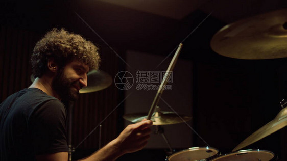 快乐摇滚鼓手在录音室演奏摇滚音乐的侧面图快乐的音乐家在音乐厅里用鼓槌敲打鼓钹格开朗的艺术图片
