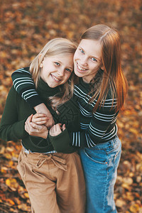 两个快乐的小女孩姐妹在秋天公园户外自然堕落时大笑玩乐和玩耍秋天图片