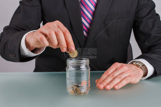 商人的手把硬币放在玻璃罐里预算规划图片