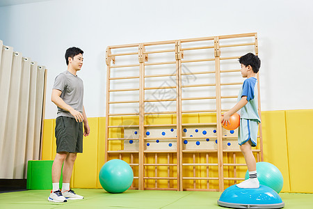 男教练指导小男孩一起玩抛球游戏图片