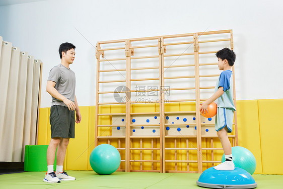 男教练指导小男孩一起玩抛球游戏图片