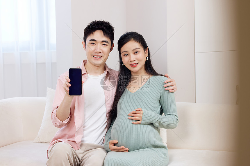 年轻怀孕的夫妻拿着手机展示图片