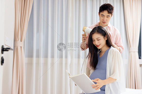 年轻男士为怀孕的妻子吹头发图片