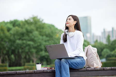 户外使用电脑学习的女学生图片