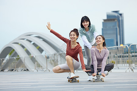 女人玩滑板女性友人一起在户外玩滑板背景