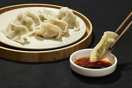 筷子夹起水饺蘸辣椒特写背景图片