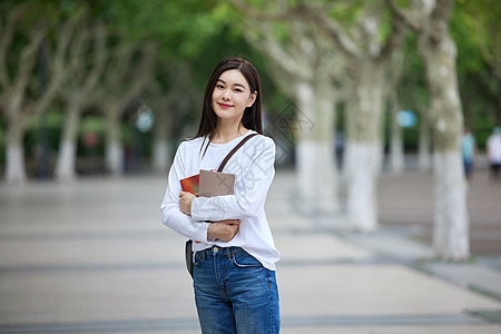 青年女休闲学习女青年校园里抱着书本背景