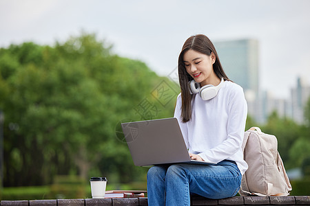 户外使用笔记本电脑的女大学生图片