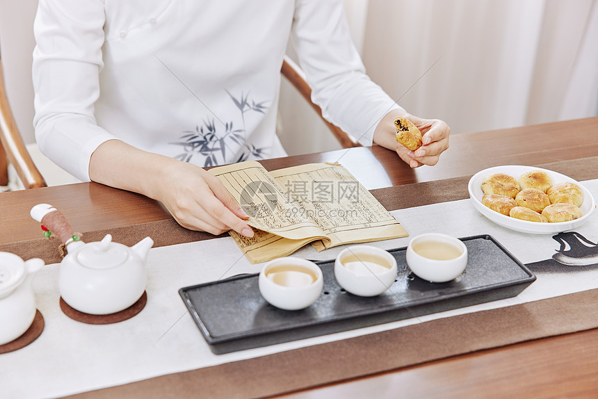 茶艺师看书品茶吃点心特写图片