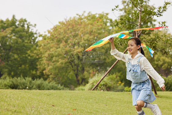 手拿风筝在草地上奔跑的小女孩图片