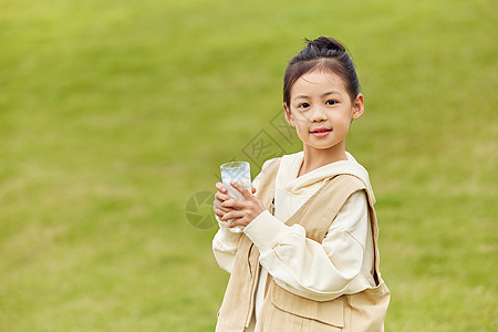 草地上手拿牛奶的小女孩图片