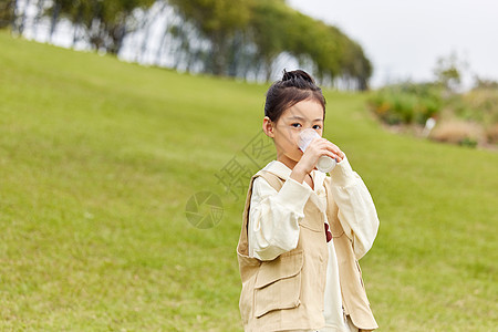 草地上喝牛奶的小女孩图片