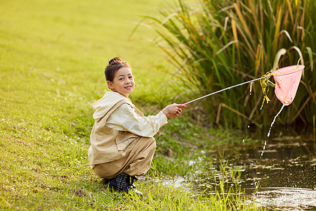 小女孩在河边捞鱼高清图片