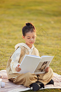 在室外草地上看书的小女孩图片