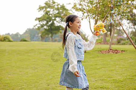 秋季室外玩泡泡机的小女孩图片