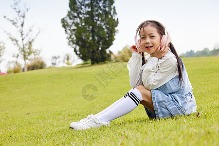 草地上戴着耳机听歌的儿童图片