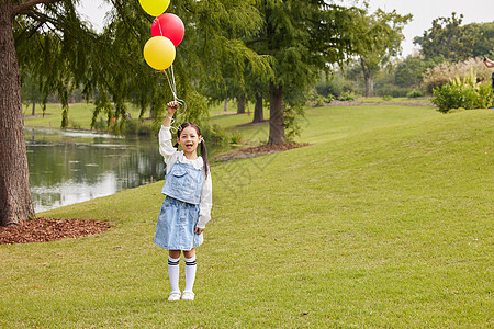 在草地上手拿气球的小女孩图片