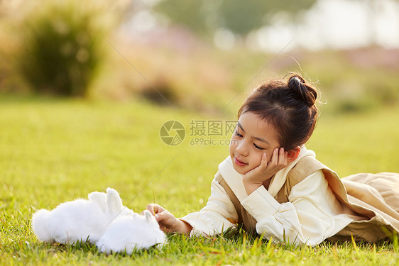 可爱女孩在草地上与兔子玩耍图片
