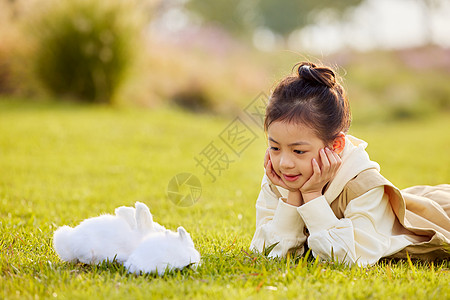 女孩在草地上与兔子玩耍图片
