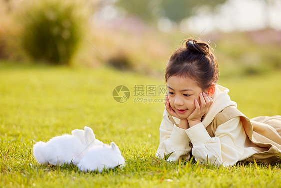 女孩在草地上与兔子玩耍图片