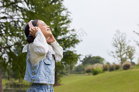 金色耳机大自然下带着耳机的小女孩背景