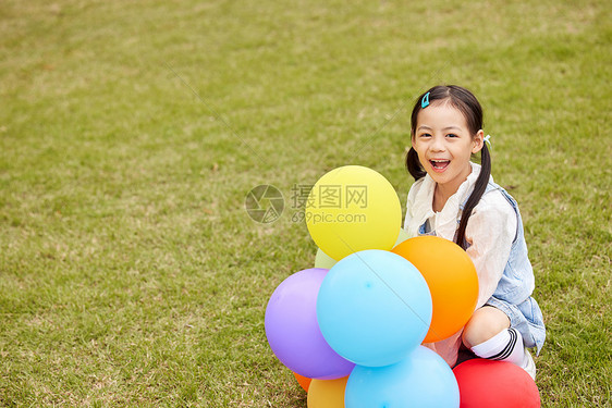 草坪上手拿气球的可爱小女孩图片