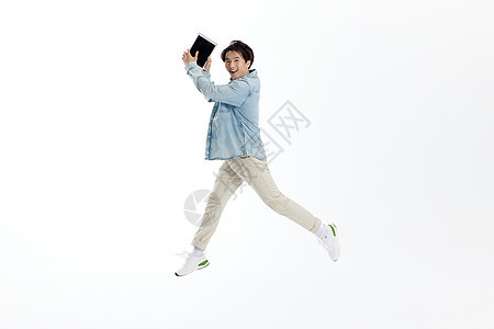 跳跃的青年男性手拿平板电脑图片