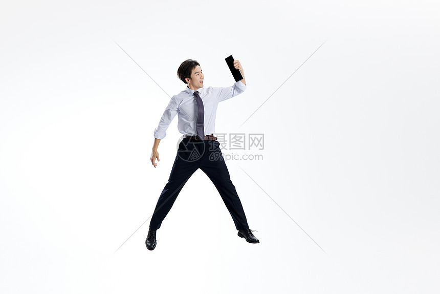 手拿平板电脑跳跃的商务男士图片