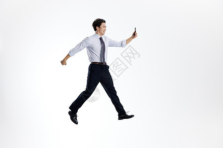 跳跃的商务男士使用手机形象图片