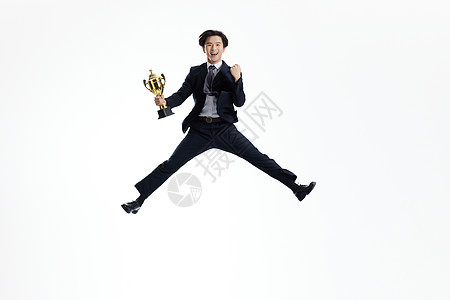 手举奖杯跳跃的商务青年男士图片