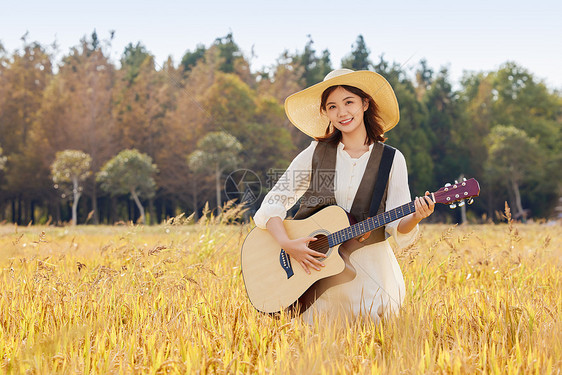站在稻田里弹奏吉他的女性图片