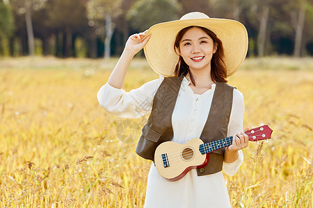 站在稻田里手拿尤克里里的女性图片