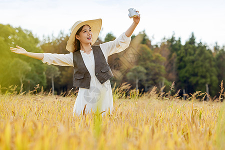 美女站在稻田里使用相机自拍高清图片