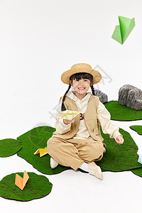 坐在草地上玩纸飞机的小女孩图片
