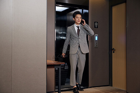 商务男士走出酒店电梯打电话图片