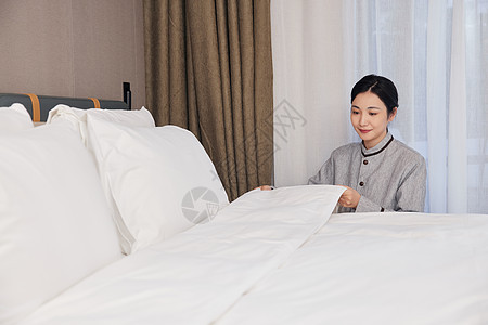 酒店服务保洁员整理客房床铺图片