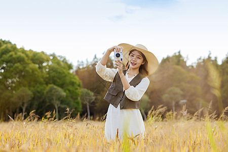 使用照相机拍照的田野美女图片