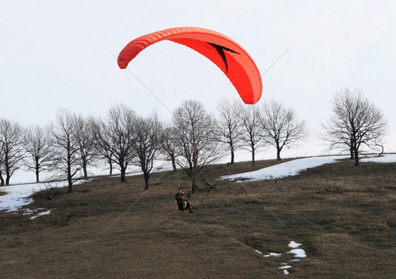 红色滑翔伞在蓝天自由翱翔图片